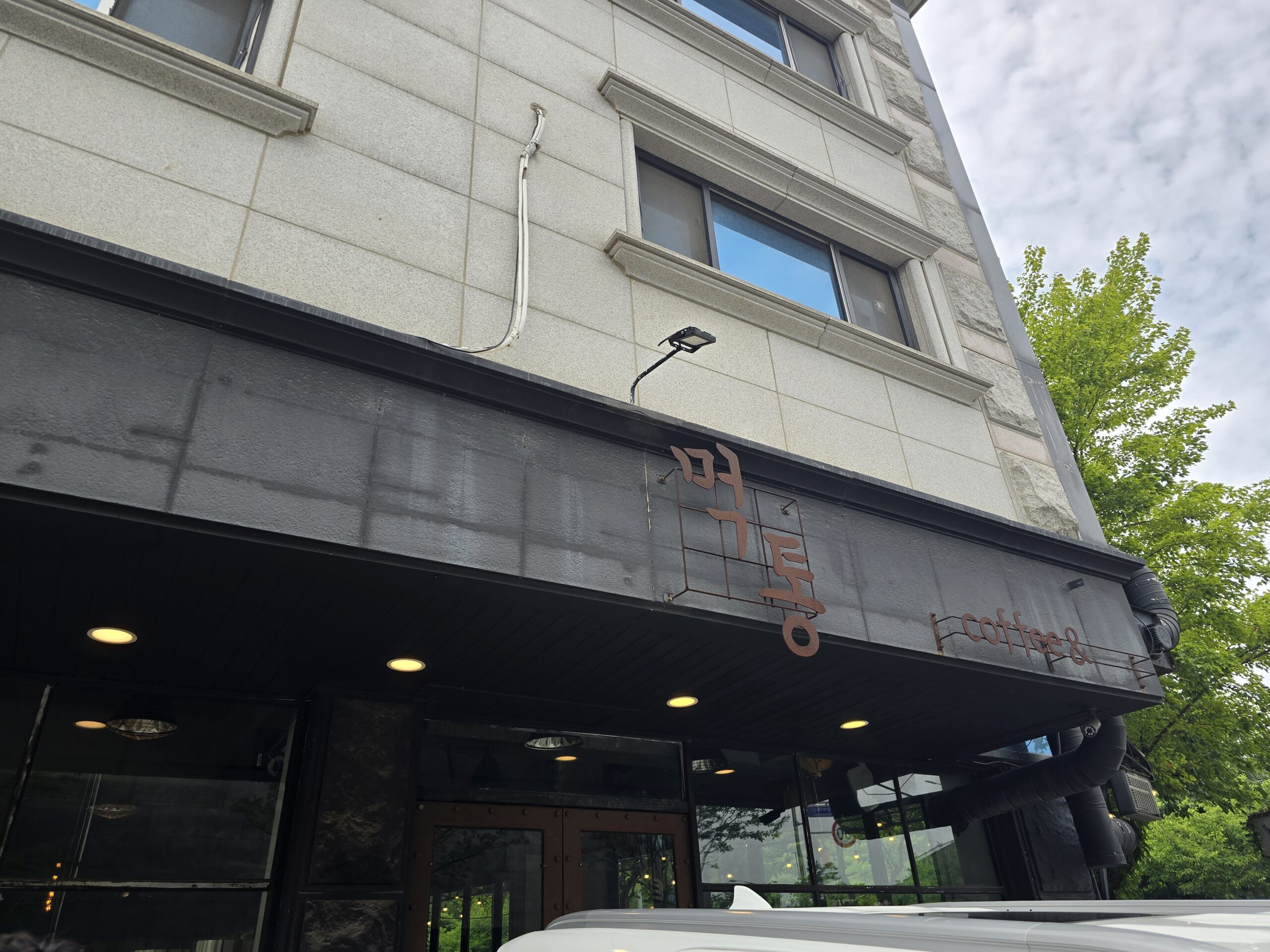 파주 먹통커피 외관 간판 - 검은 캐노피에 붉은 철제 레터링