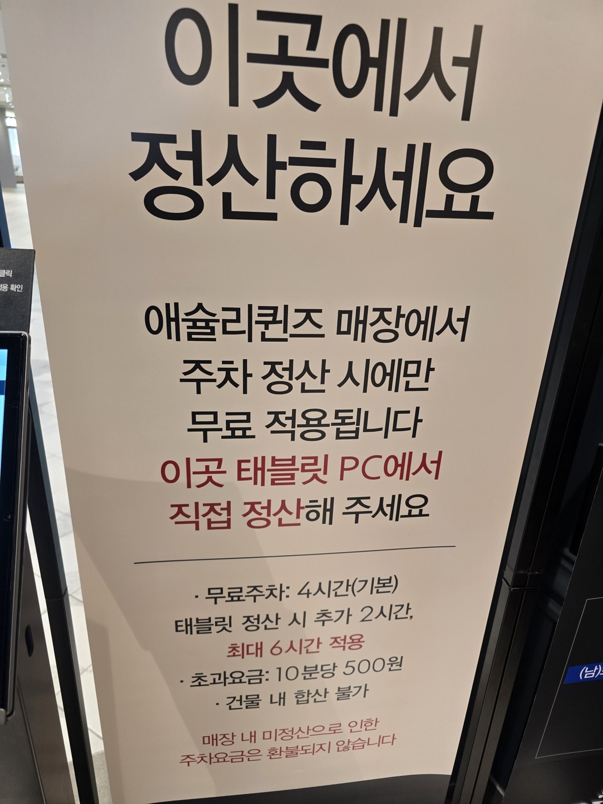 애슐리퀸즈 운정점 매장 안 주차 정산 안내판 원문, 무료주차 4시간 기본과 태블릿 정산 시 추가 2시간 (15:49 촬영)